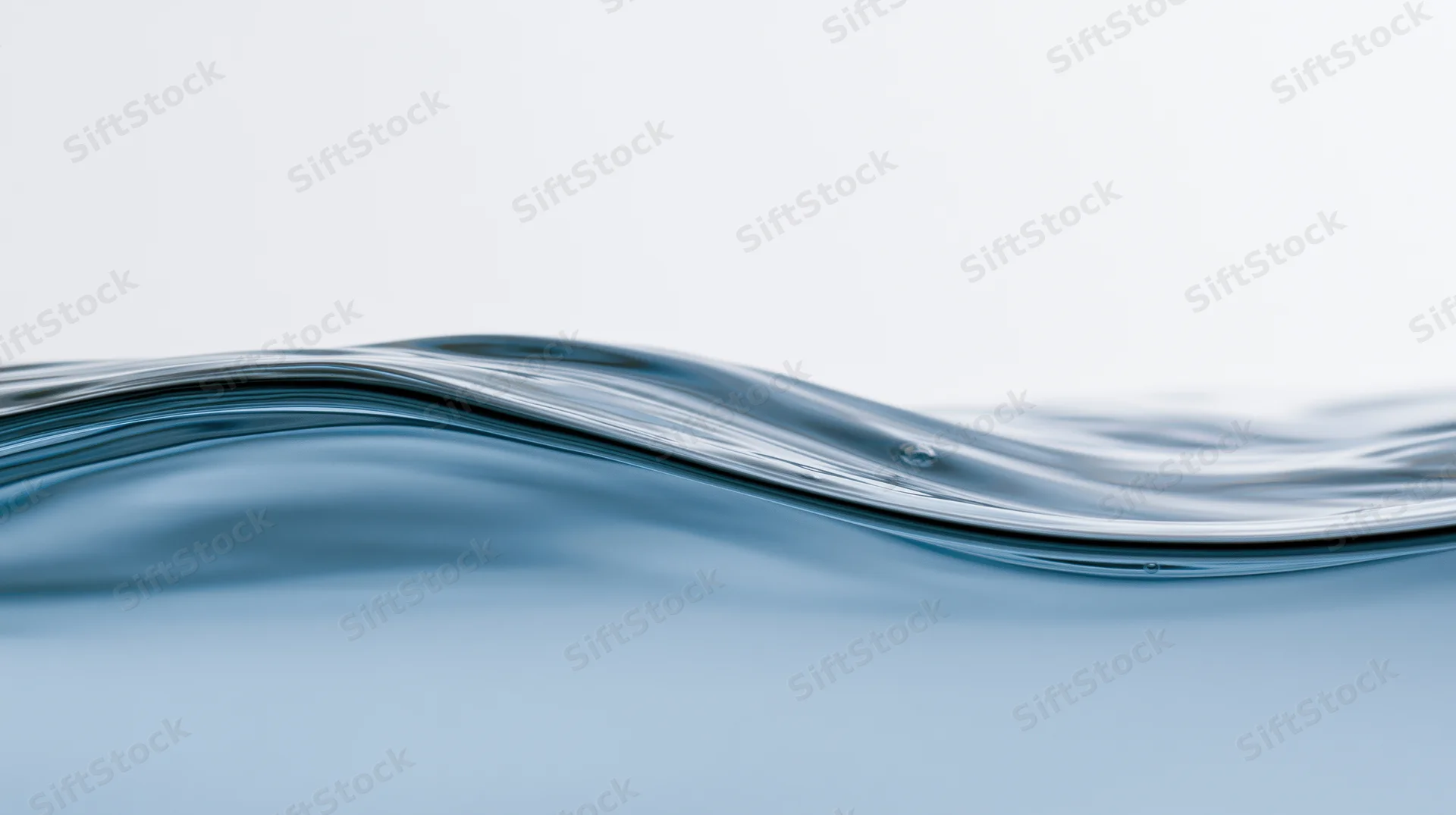 Close-up of a rippling water surface with a smooth wave and subtle reflection against a light background