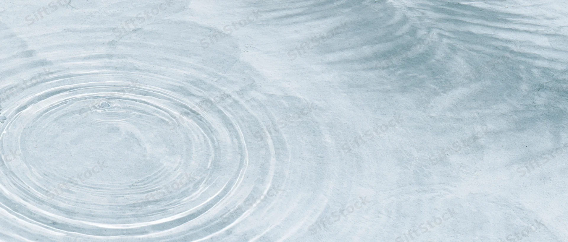 Concentric ripples spreading across a clear shallow water surface viewed from above