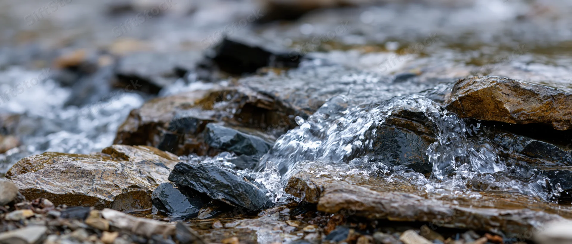 Clear water flowing over jagged wet rocks in a natural stream setting