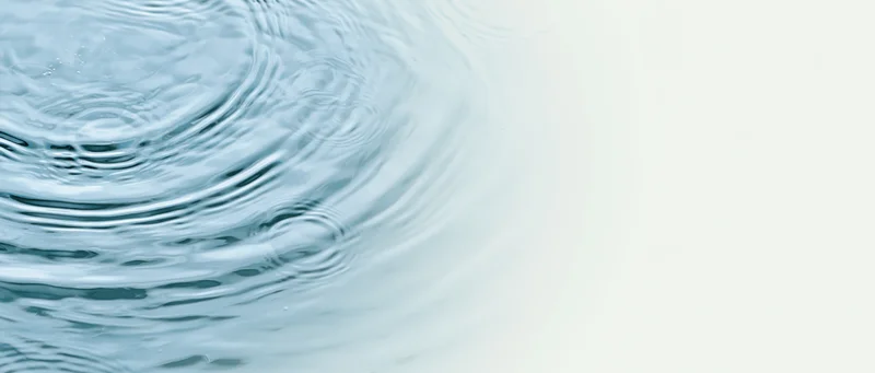 Rippling water surface with concentric circles and light gradient background