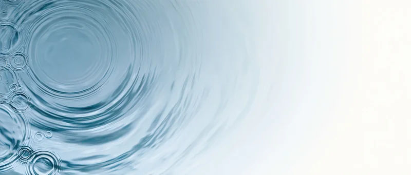 Water surface with concentric ripples and droplets on left, fading to white on right