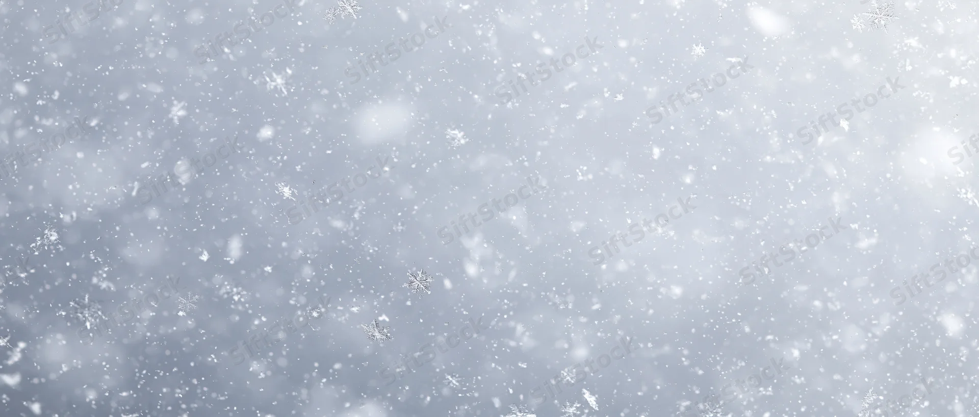 Falling snowflakes in a soft winter sky with blurred background and copyspace