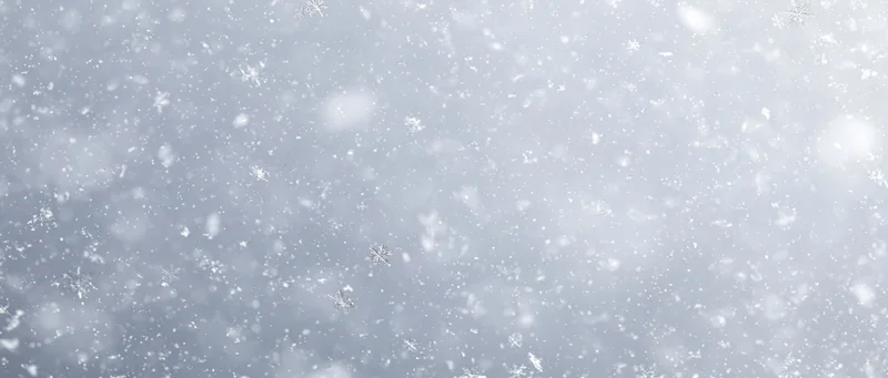 Falling snowflakes in a soft winter sky with blurred background and copyspace