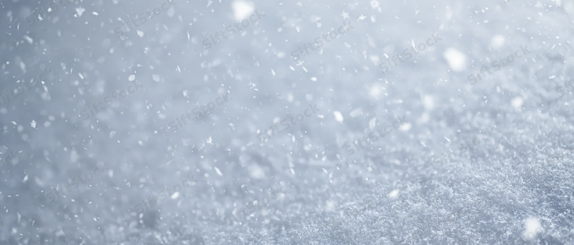 Falling snow in soft focus against a pale winter sky