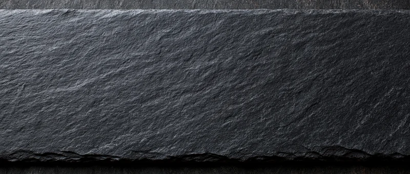 Close-up of dark natural slate stone surface with rough texture and uneven edges