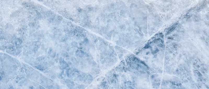 Close-up of natural ice surface with cracks and frost patterns filling the frame