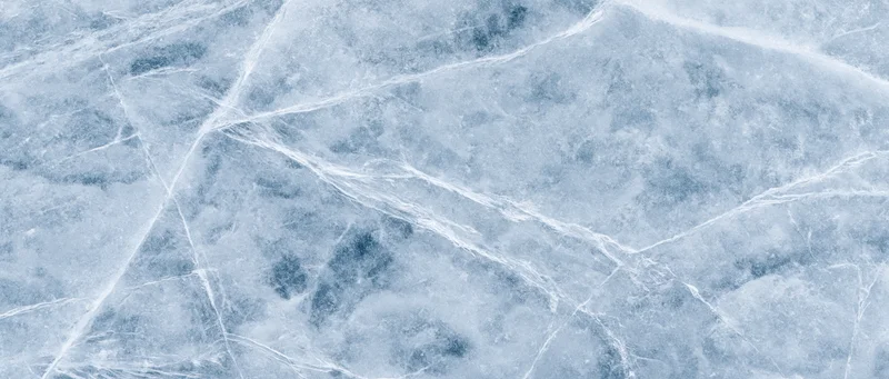 Close-up flat lay of a natural ice surface filling the entire frame with cracks and frost patterns