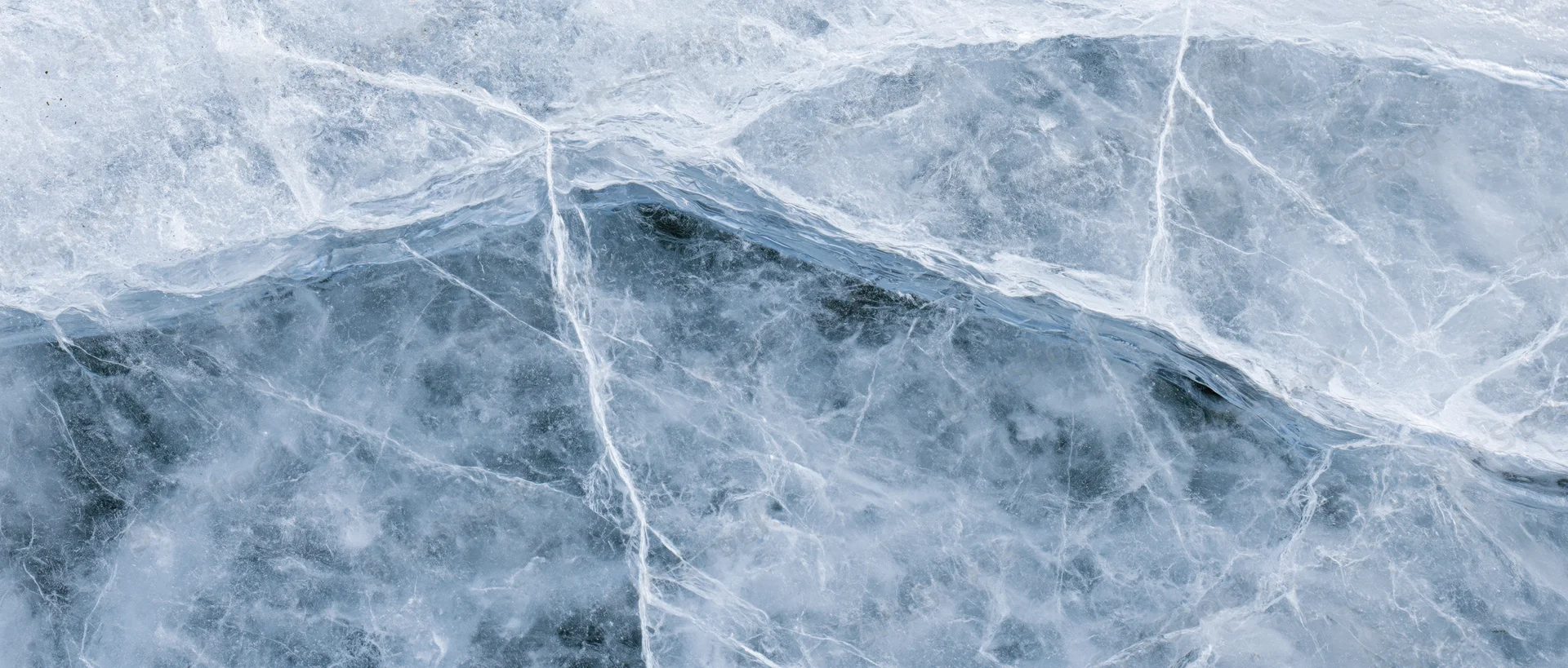 Close-up of natural ice surface with cracks and blue-gray textures filling the frame