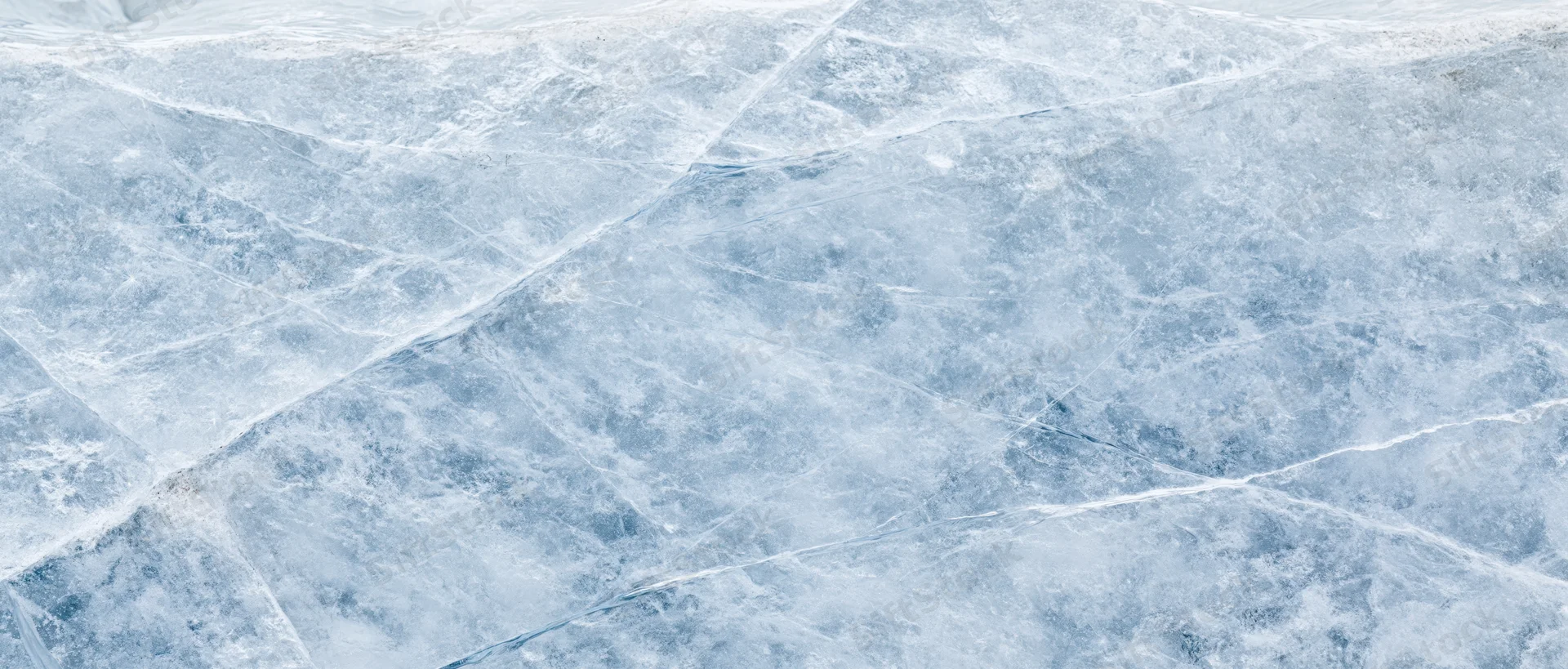 Close-up of natural ice surface with cracks and frost patterns filling the frame