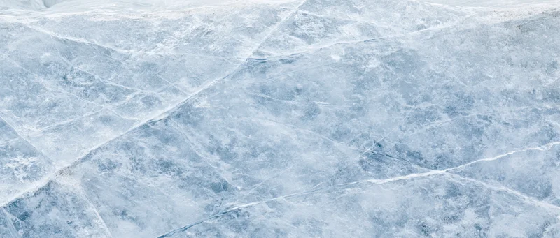 Close-up of natural ice surface with cracks and frost patterns filling the frame