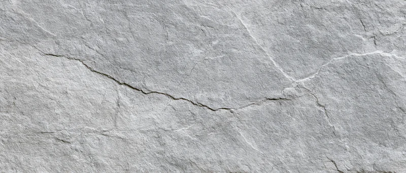 Close-up of cracked gray stone surface with natural texture and fissures