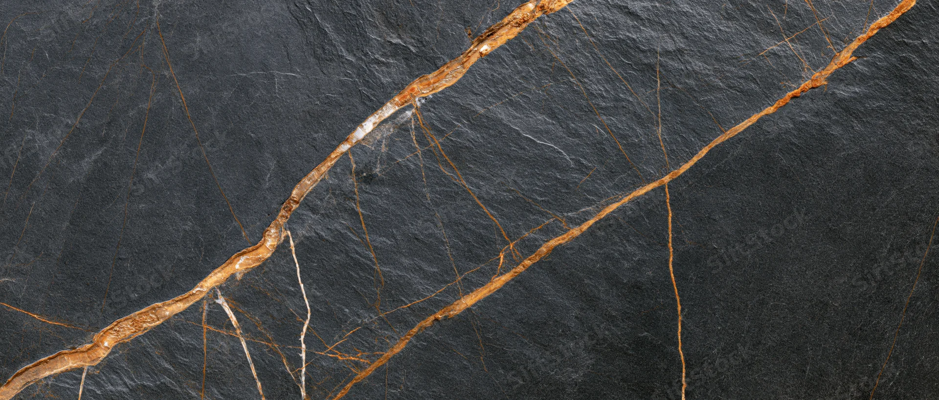 Close-up of polished black marble slab with gold and brown veining