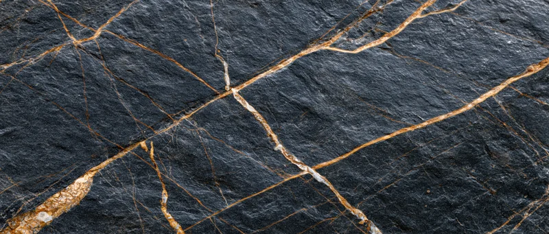 Close-up of polished black marble slab with gold and white veining across its surface