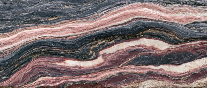 Polished metamorphic rock slab with wavy layered texture filling the frame