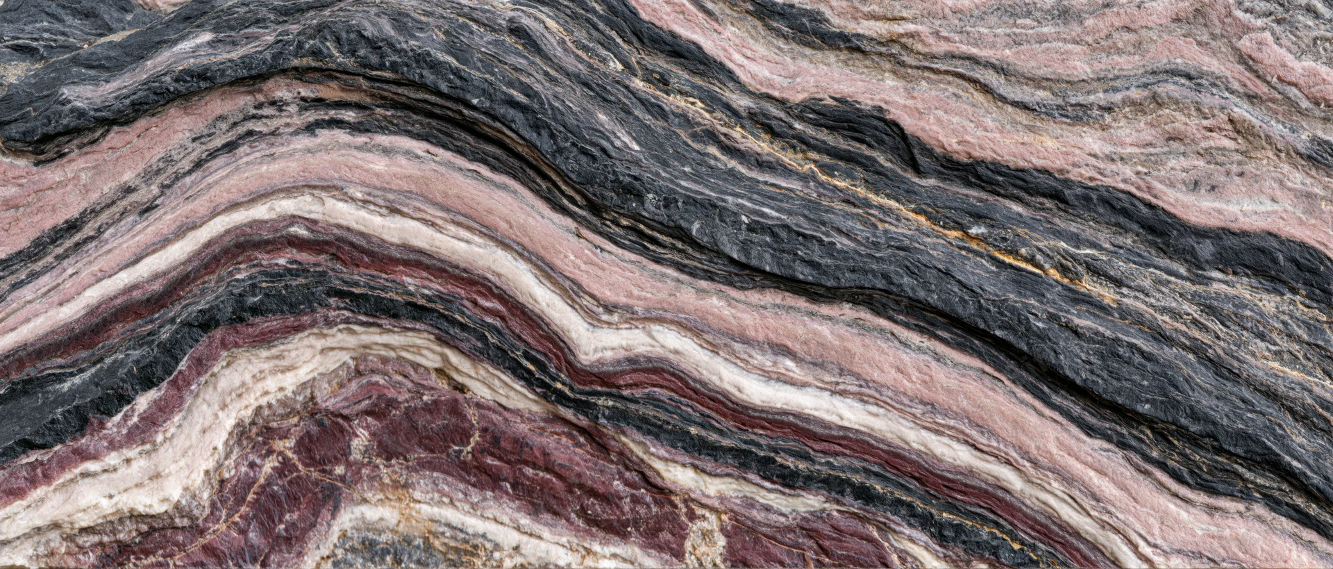 Polished metamorphic rock slab with wavy layered texture filling the frame
