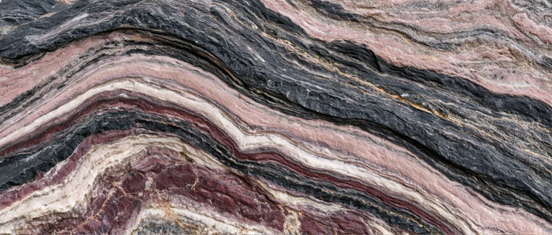 Polished metamorphic rock slab with wavy layered texture filling the frame