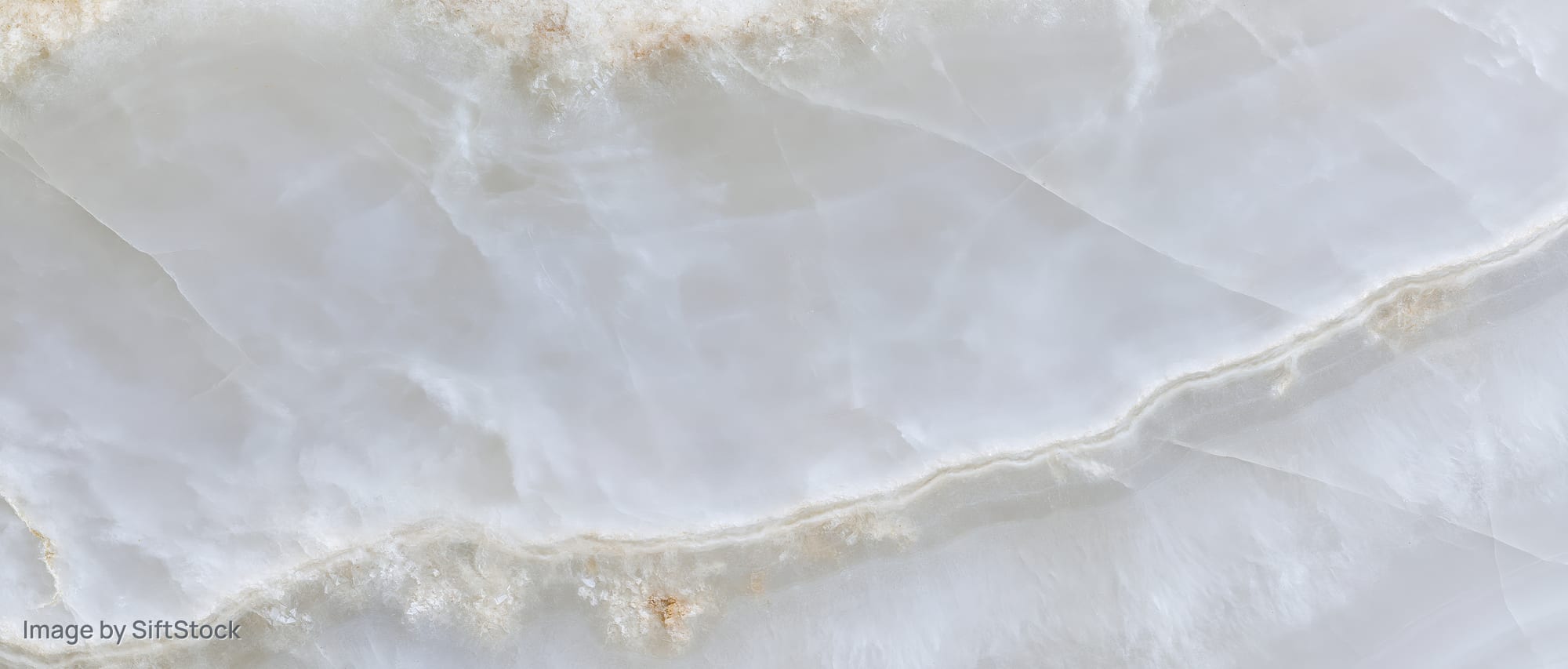Close-up of a polished white onyx marble slab surface with natural veining and crystalline texture