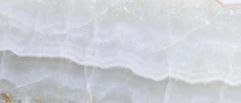 Close-up of polished white onyx marble slab surface showing natural veined texture and layered pattern