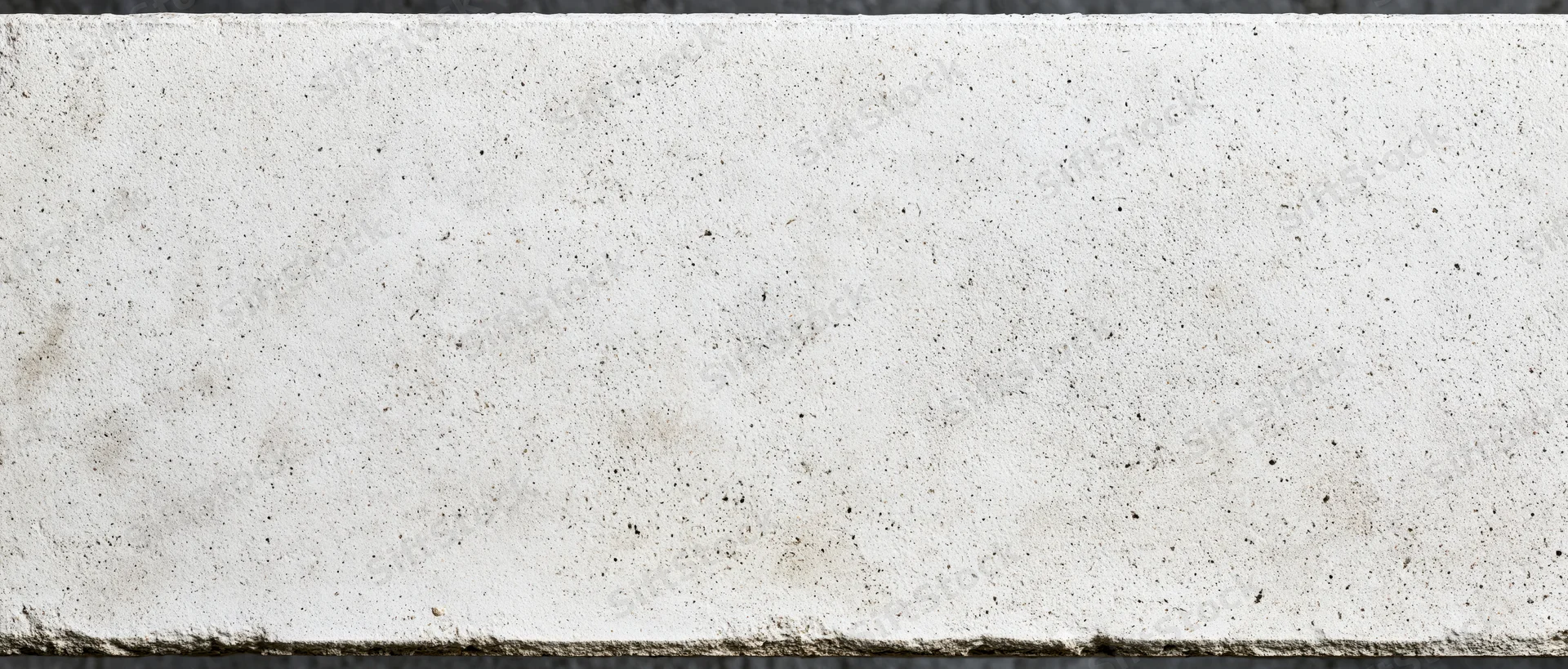 Close-up of a rough concrete wall surface with speckled texture and horizontal edges