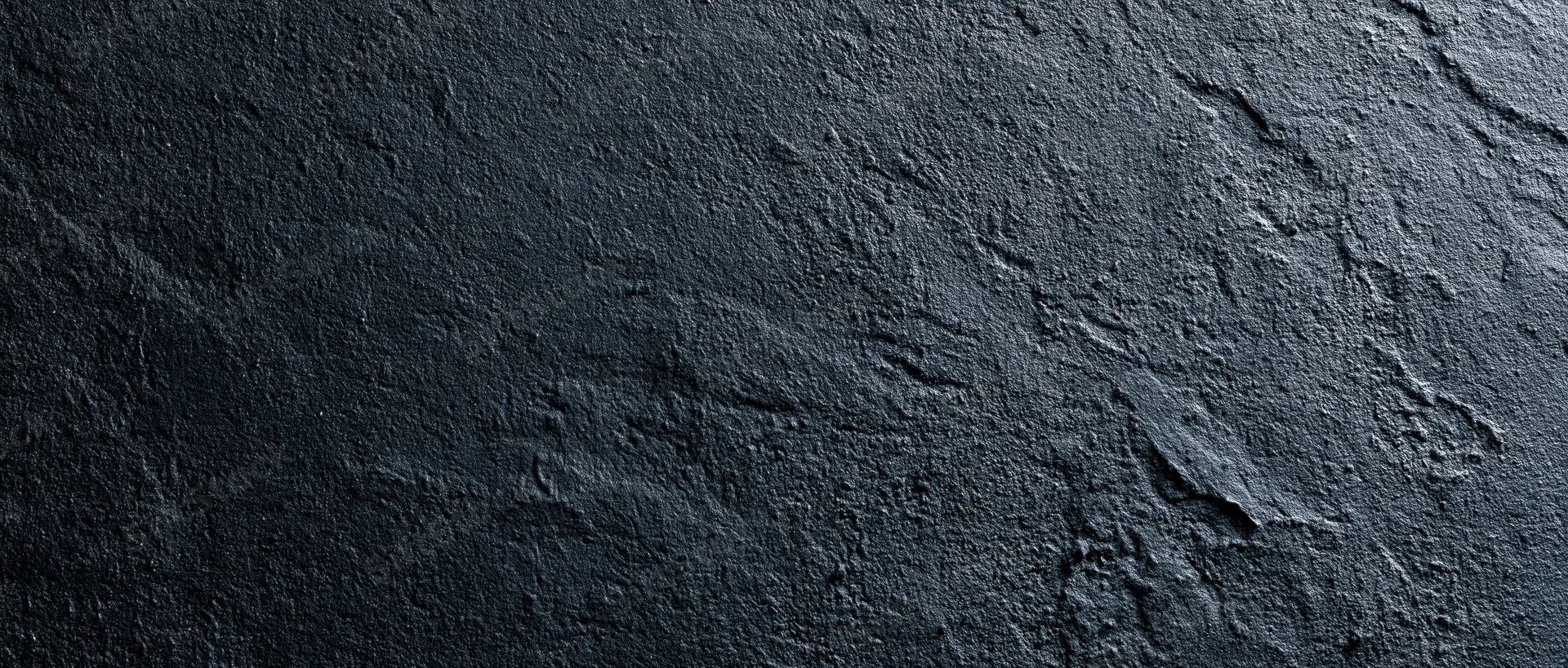 Close-up of rough dark concrete wall surface with visible texture and cracks