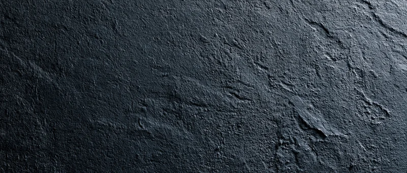 Close-up of rough dark concrete wall surface with visible texture and cracks