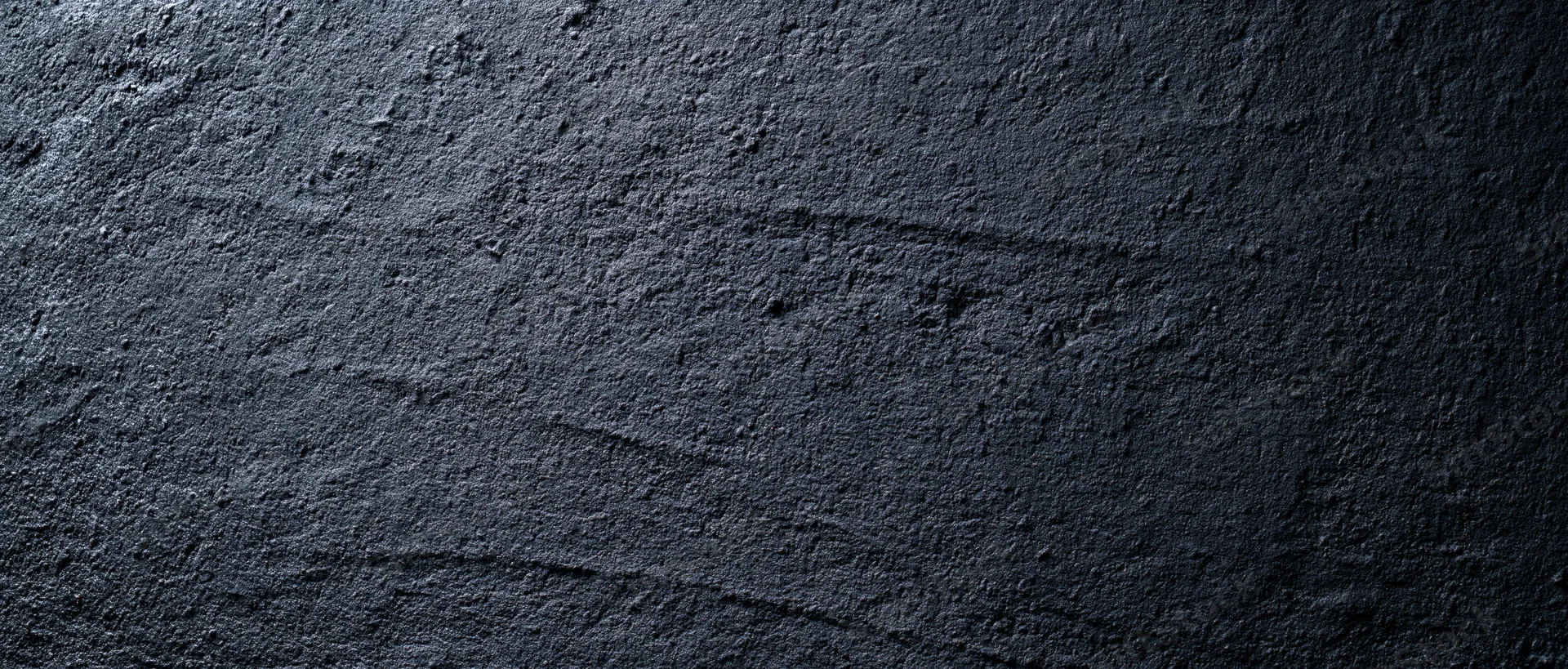 Close-up of rough dark concrete wall surface with visible texture and cracks
