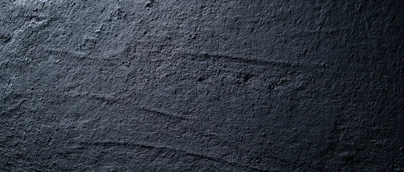 Close-up of rough dark concrete wall surface with visible texture and cracks