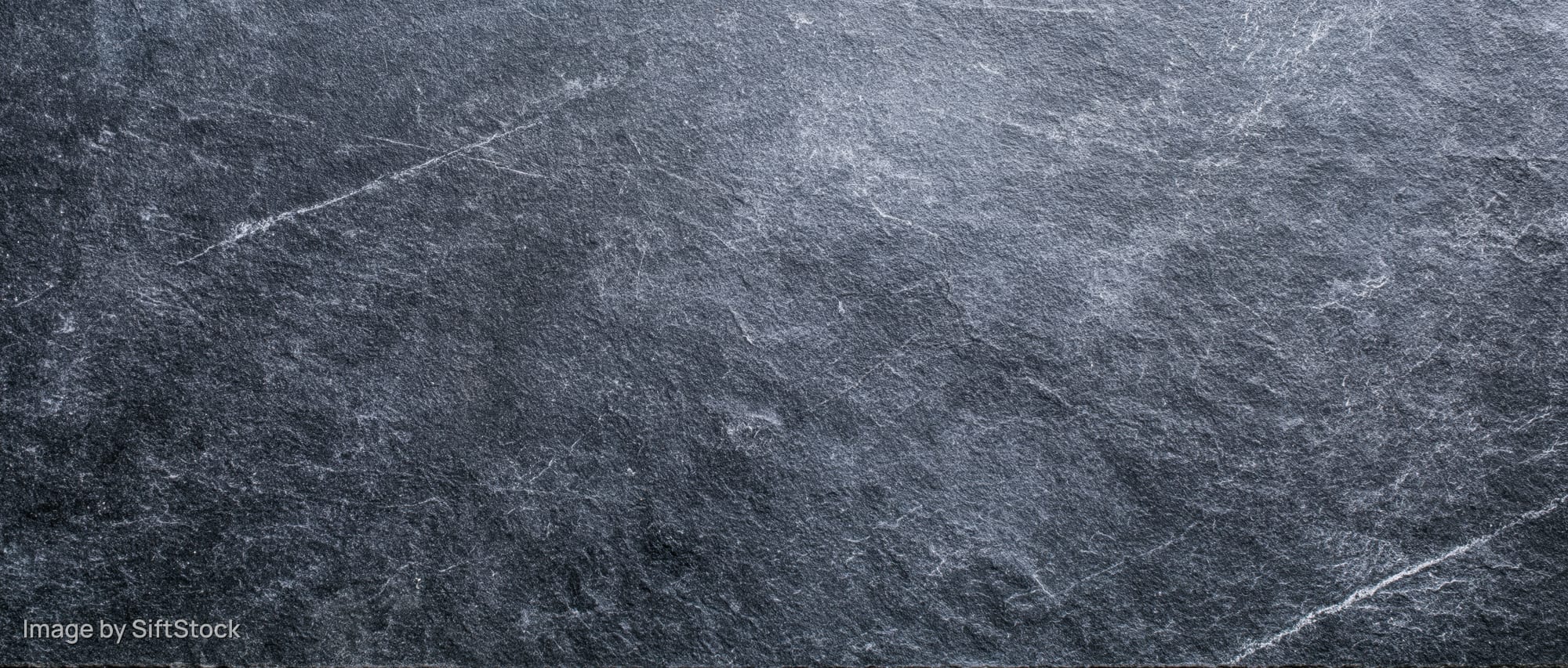 Close-up of rough dark slate surface with natural veining and texture