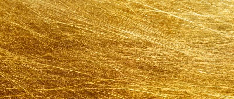 Close-up of scratched gold metal surface filling the frame