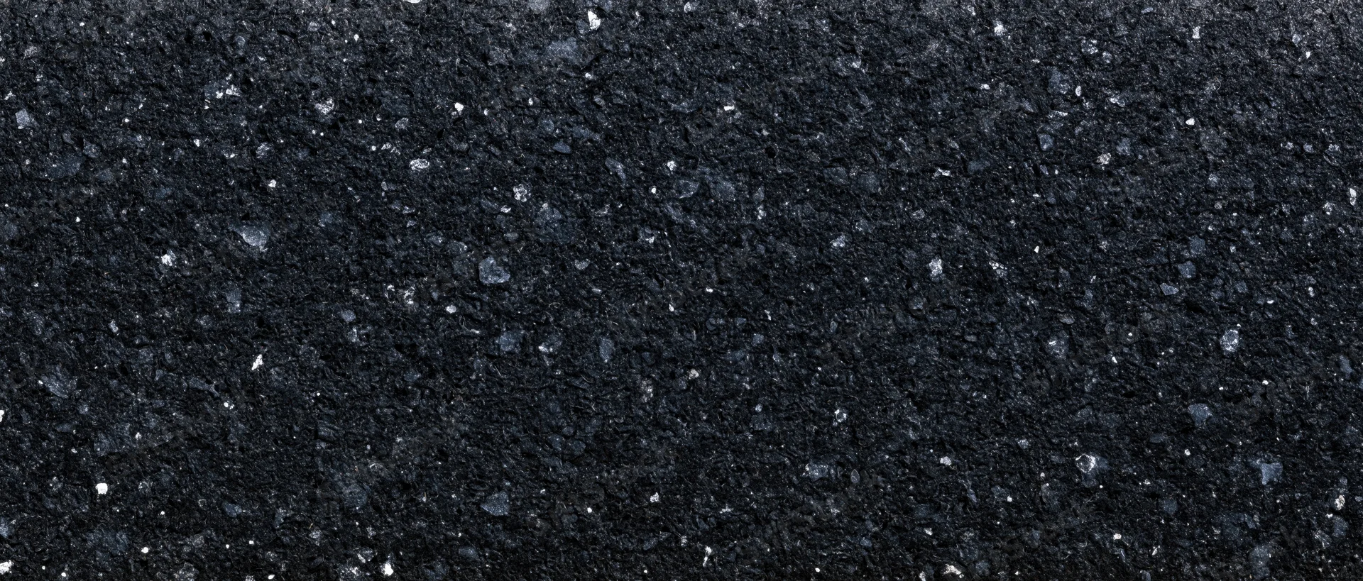 Close-up of dark coarse asphalt surface with granular texture