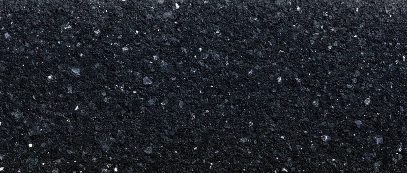 Close-up of dark coarse asphalt surface with granular texture