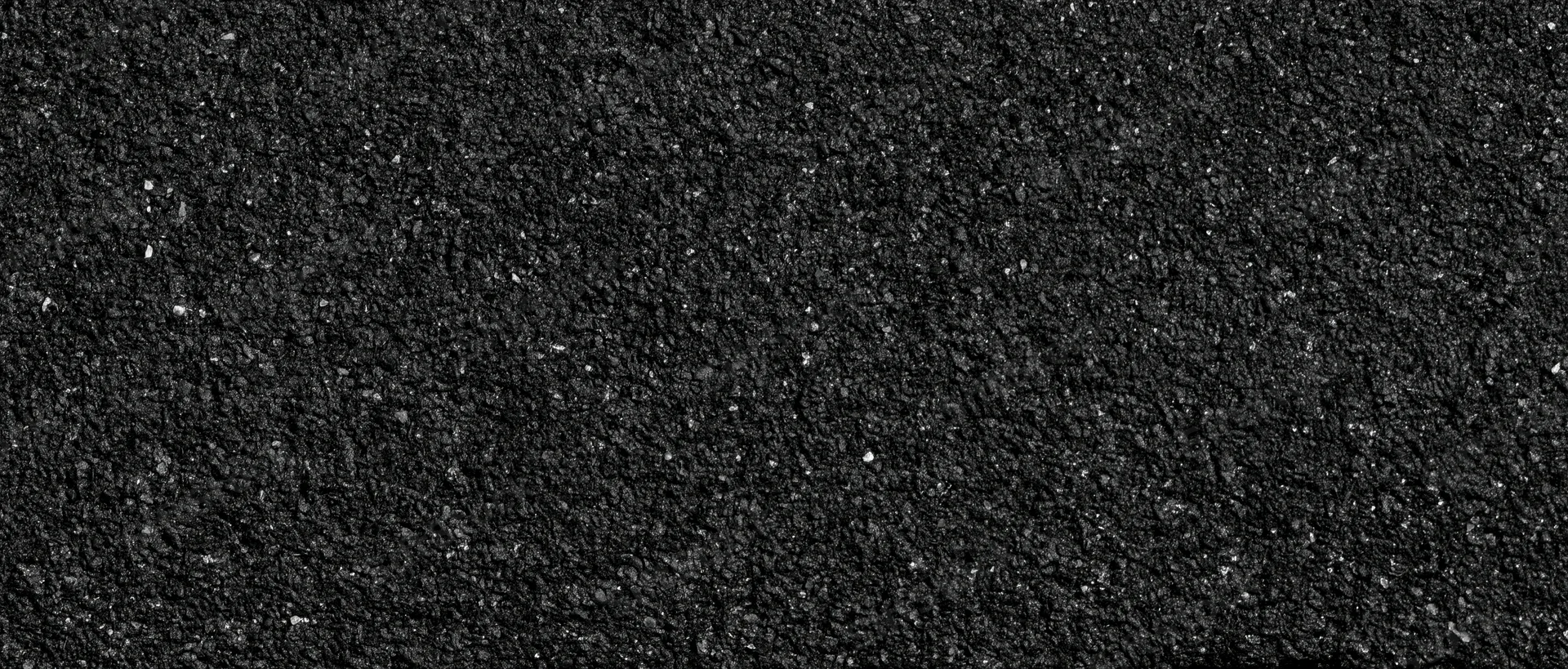 Close-up of coarse dark asphalt surface with granular texture