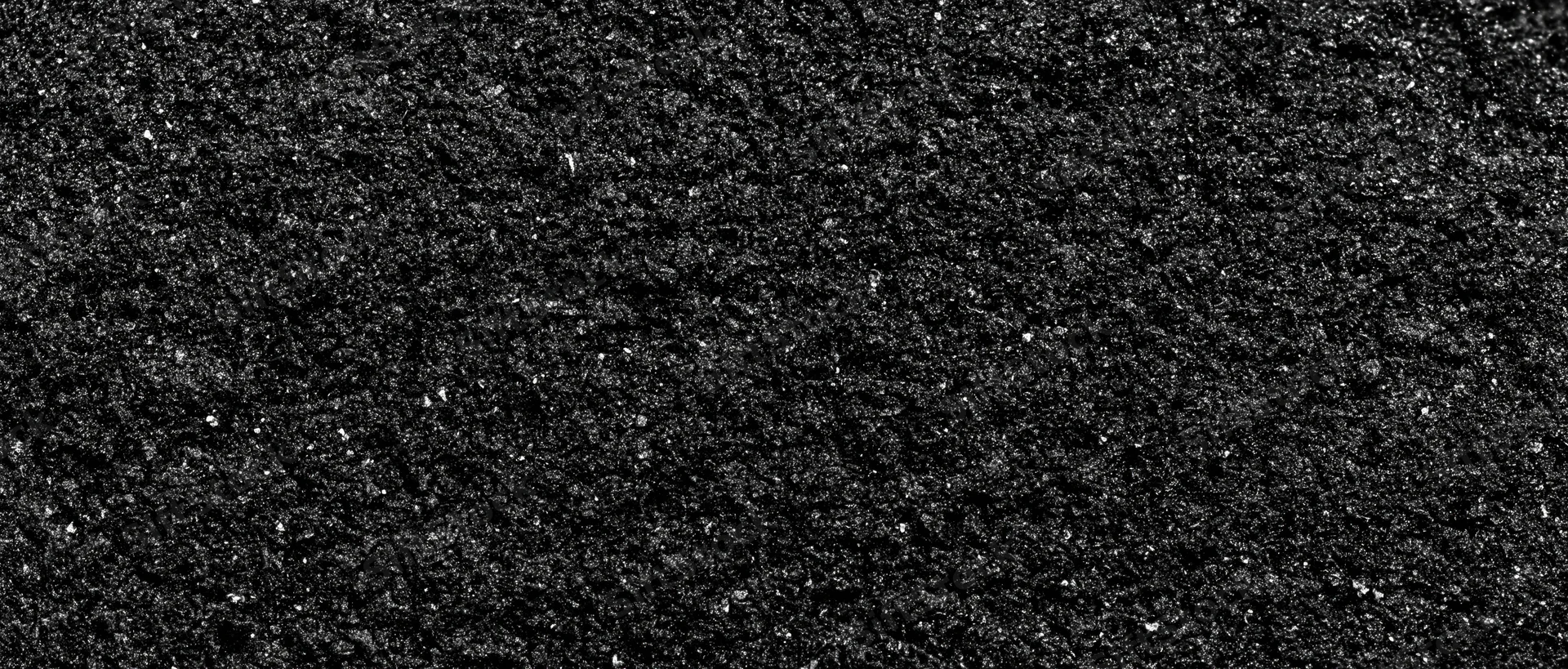 Close-up of coarse dark asphalt surface showing granular texture and rough detail