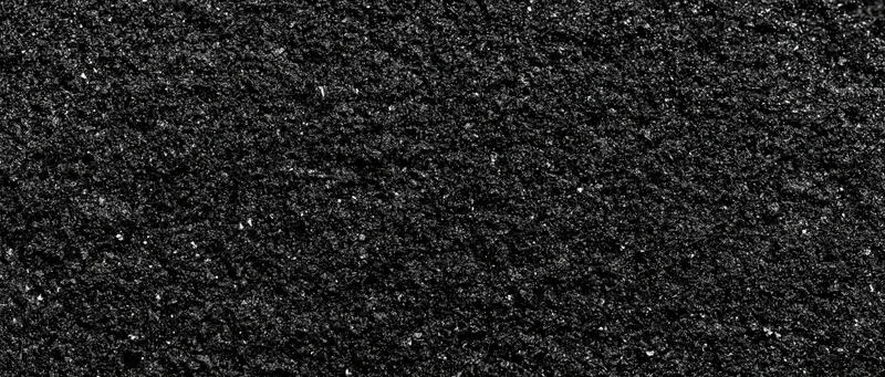 Close-up of coarse dark asphalt surface showing granular texture and rough detail