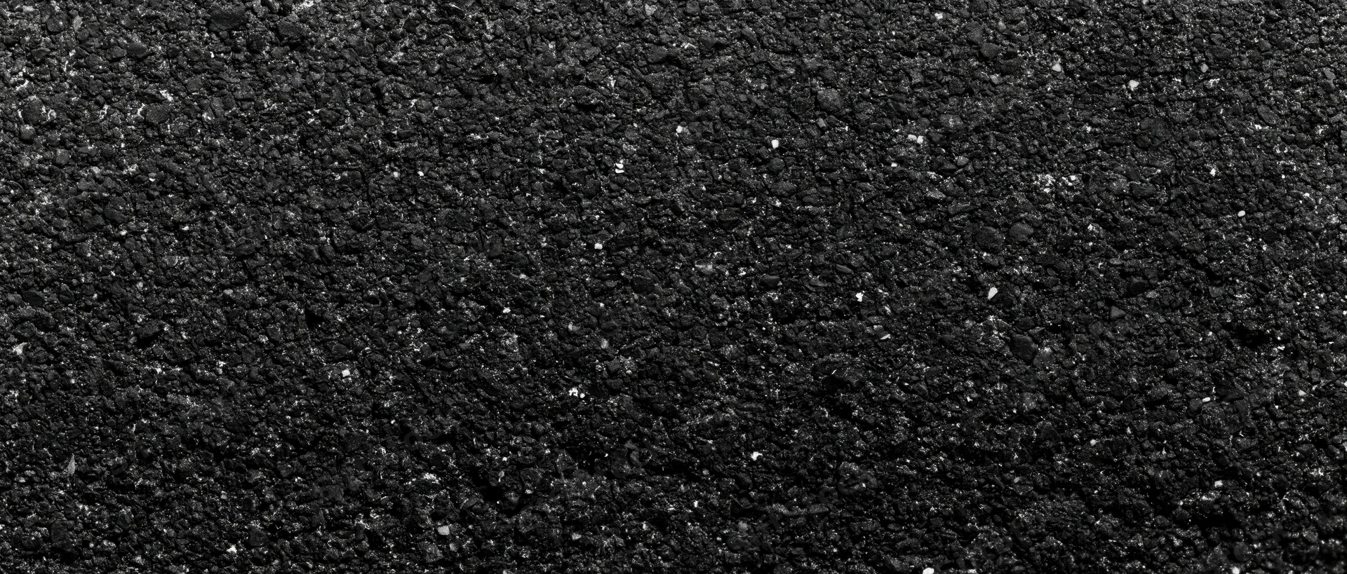 Close-up of coarse dark asphalt surface with granular texture