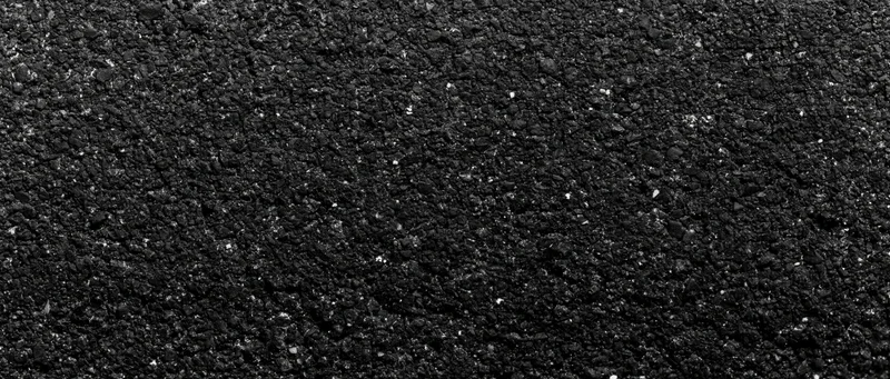 Close-up of coarse dark asphalt surface with granular texture