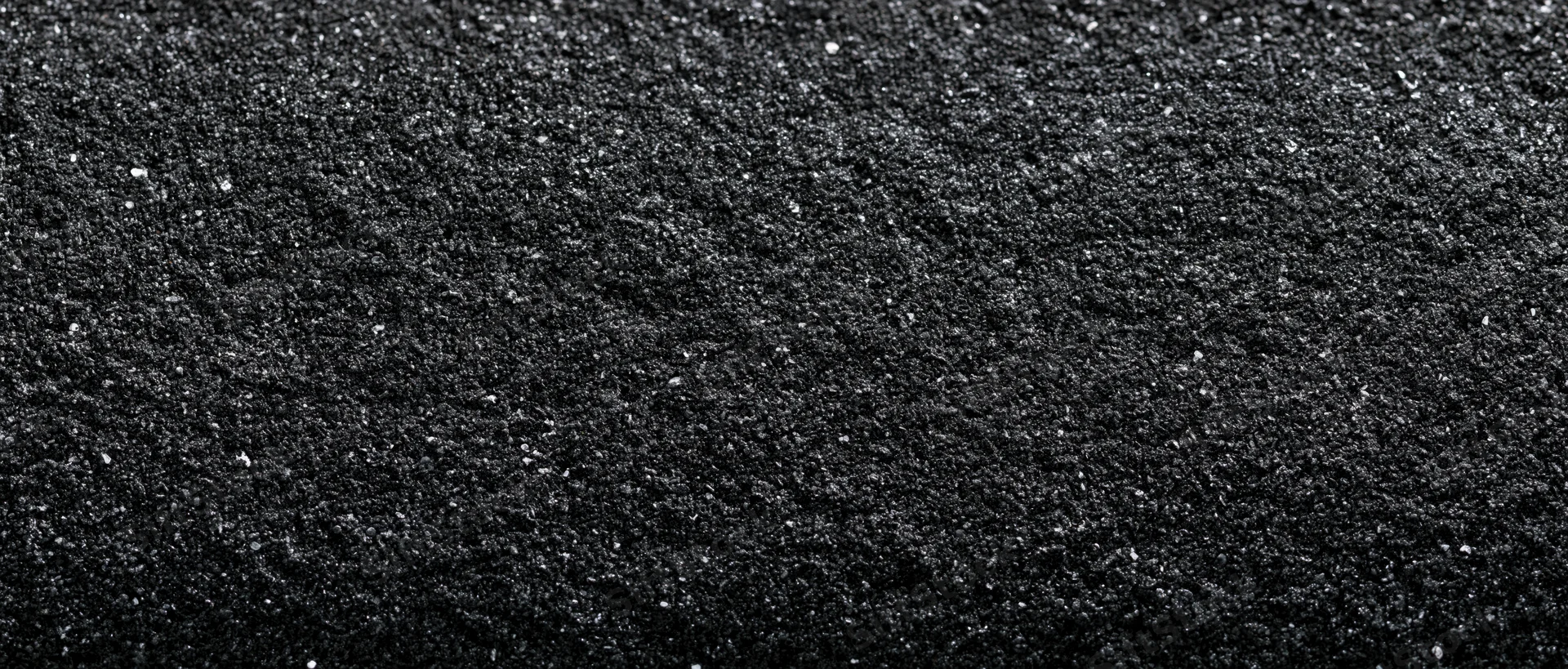 Close-up of dark asphalt surface with granular texture