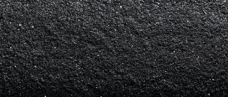 Close-up of dark asphalt surface with granular texture