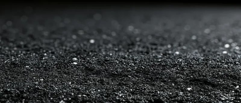 Close-up of dark asphalt surface with scattered gravel and shallow depth of field