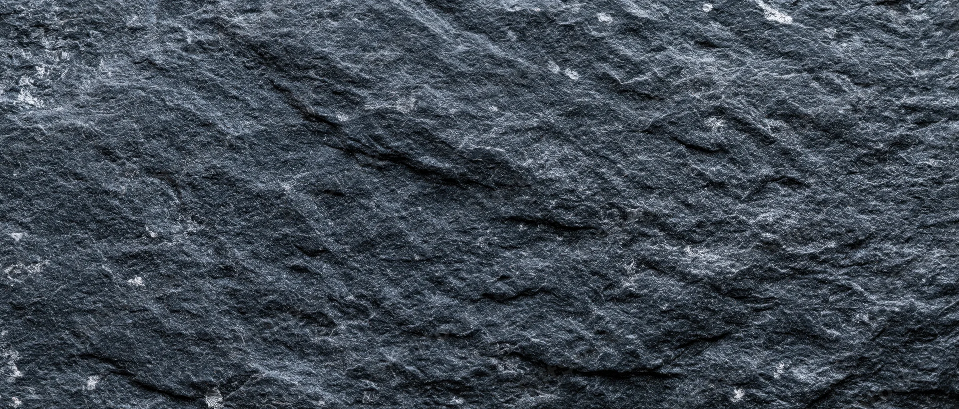 Close-up of dark slate stone surface with rough texture filling the frame
