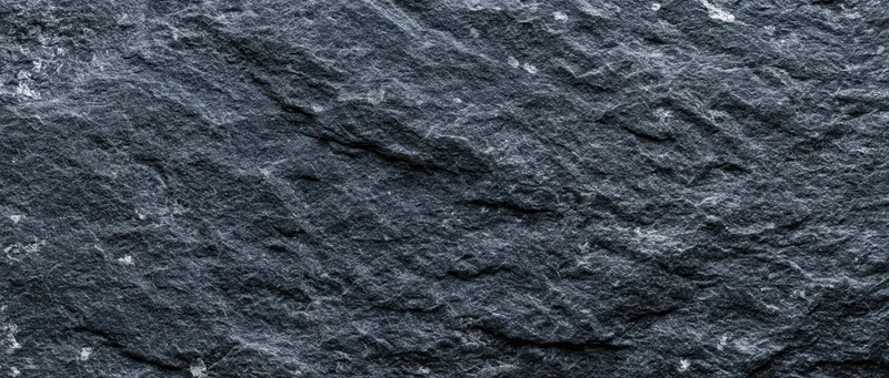 Close-up of dark slate stone surface with rough texture filling the frame