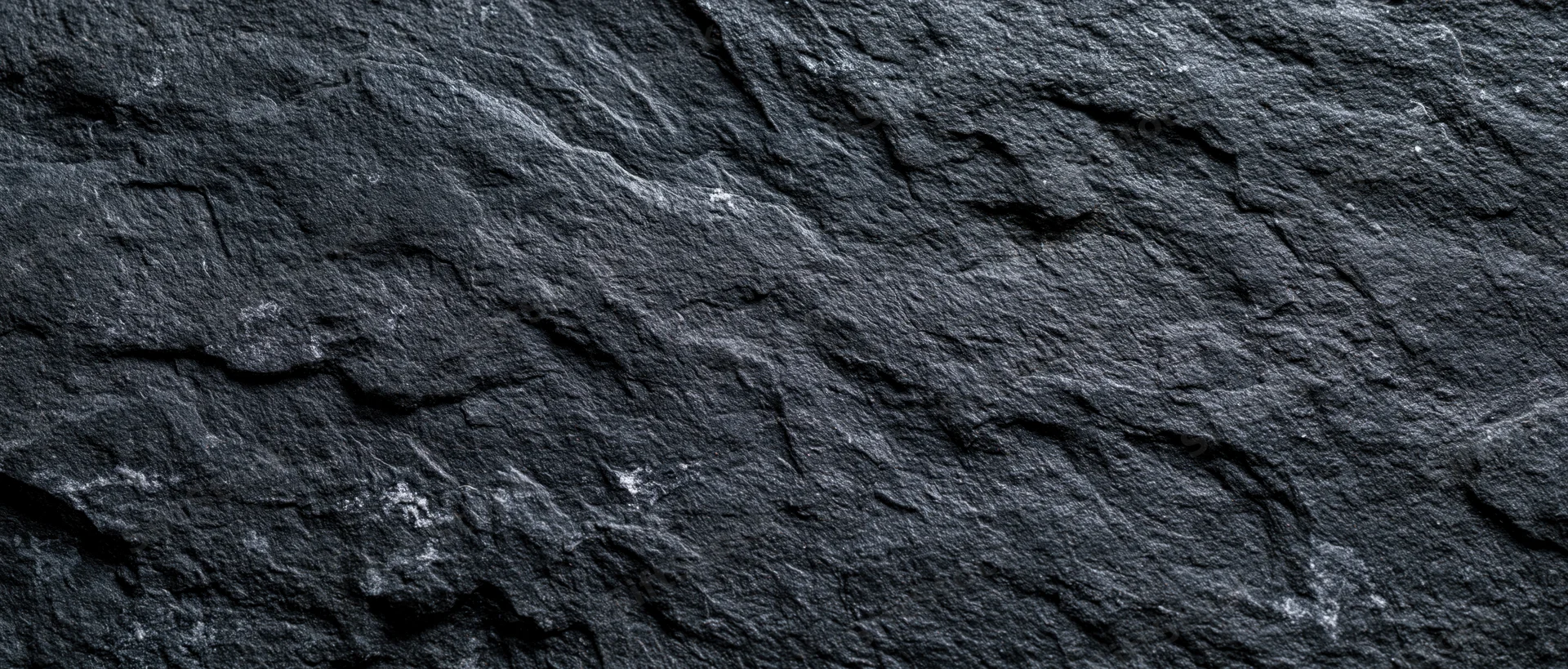 Close-up of dark slate stone surface with rough texture and natural cracks