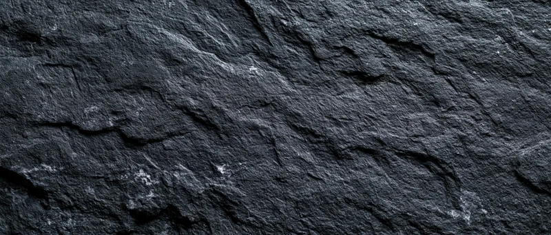 Close-up of dark slate stone surface with rough texture and natural cracks