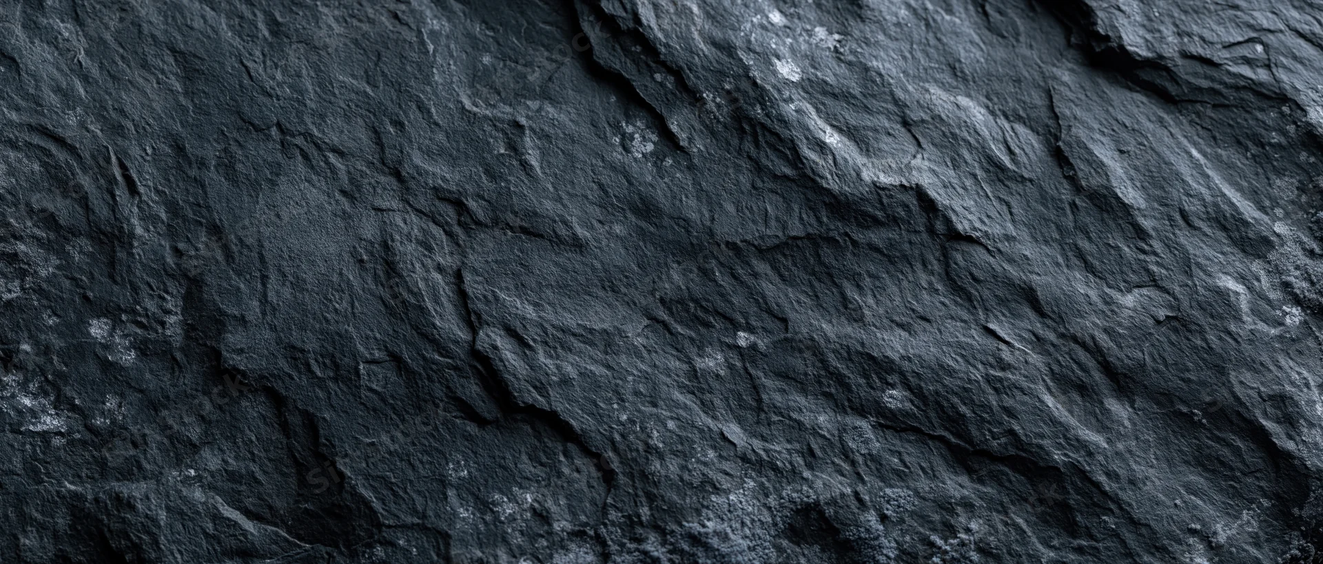 Close-up of dark slate stone surface with natural cracks and layers