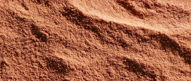 Close-up of coarse dry sand surface with ripples and texture filling the frame