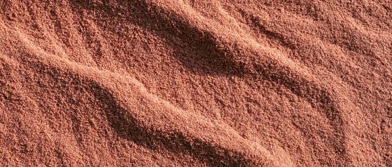 Closeup of coarse dry sand surface with rippled texture filling the frame
