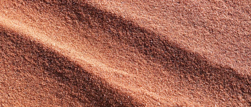 Close-up of dry coarse sand surface with rippled texture filling the frame