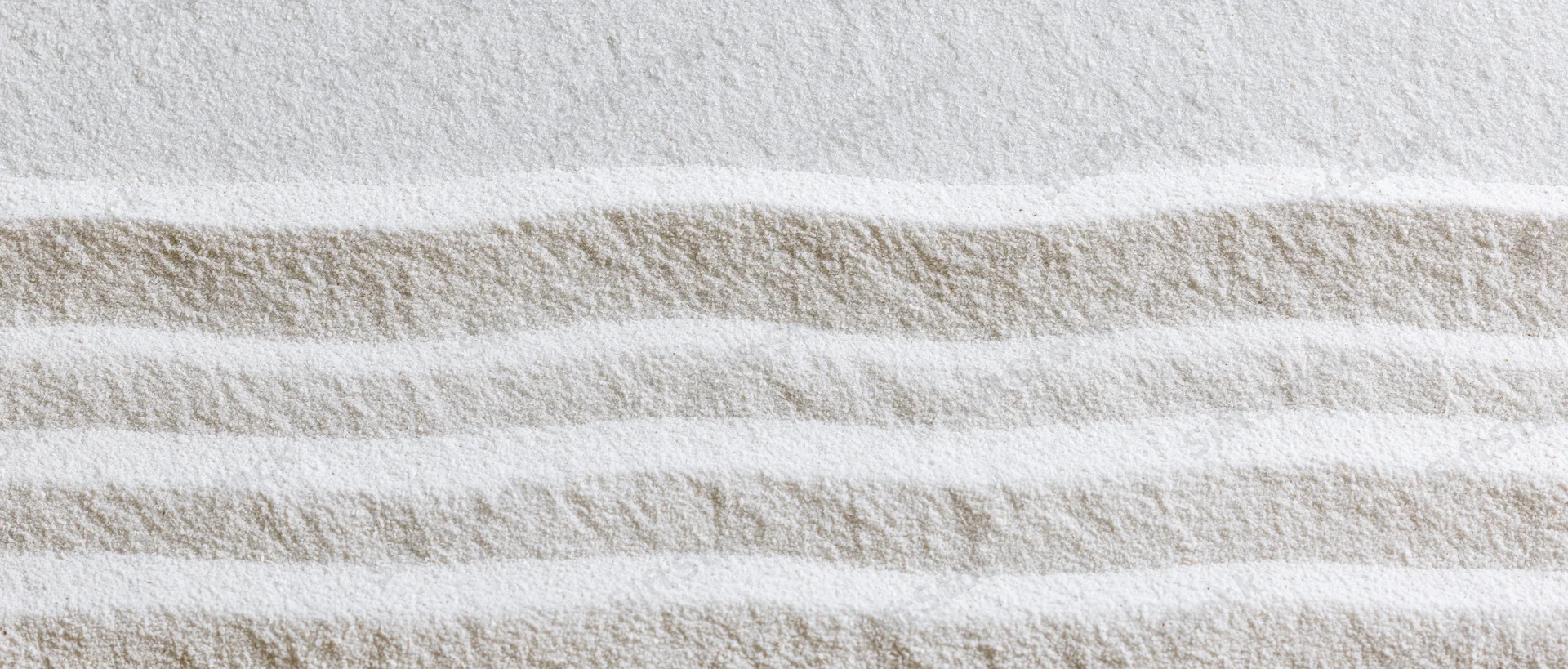 Raked white sand in a zen garden forming horizontal stripes with soft texture