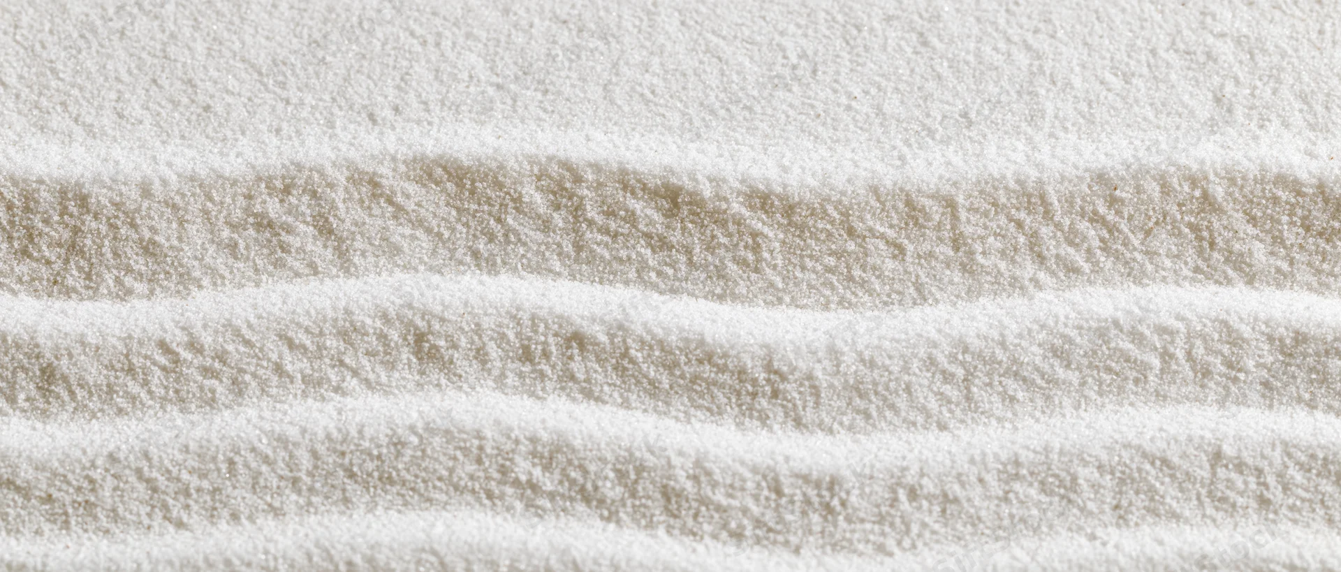 Raked white sand in a zen garden forming parallel lines and stripes
