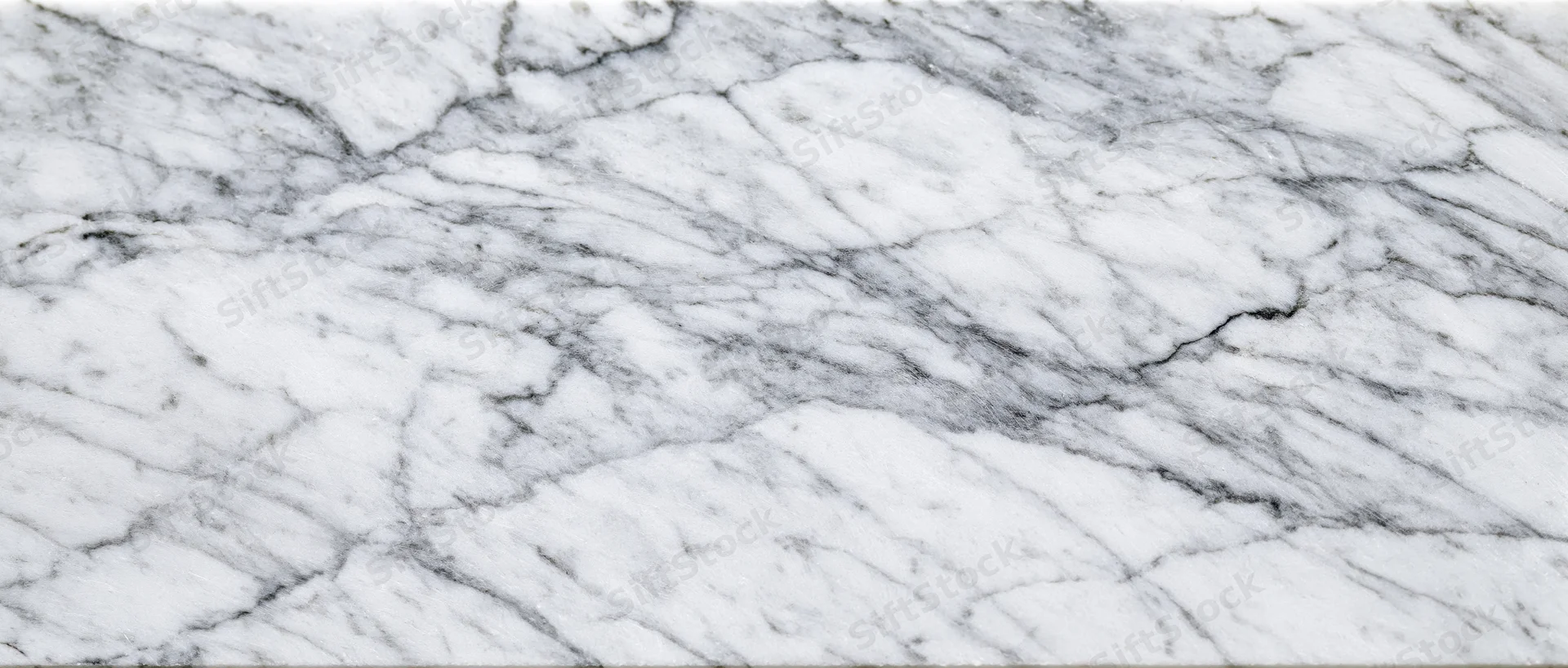 Close-up of white carrara marble surface with natural gray veining filling the frame